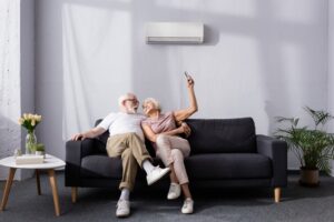 senior-couple-on-couch-changing-temperature-of-mini-split-on-wall-with-remote